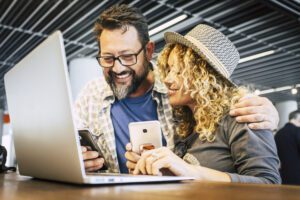 Two people engrossed in their phones at a table, seemingly unaware of what's happening around them, representing the contrast between nomad vs expat lifestyles