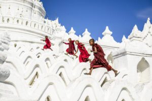 Asian monks running on white temple walls, Hsinbyume Pagoda, Mandalay, Sagaing, Myanmar