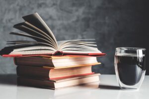 A cup of coffee near of stack of books on grey background