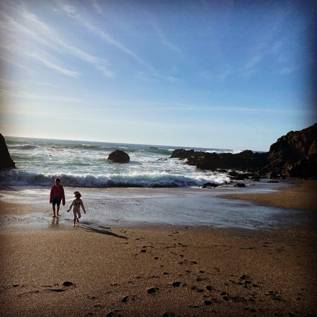 Two kids on a small cove beach at Bodega Bay, California