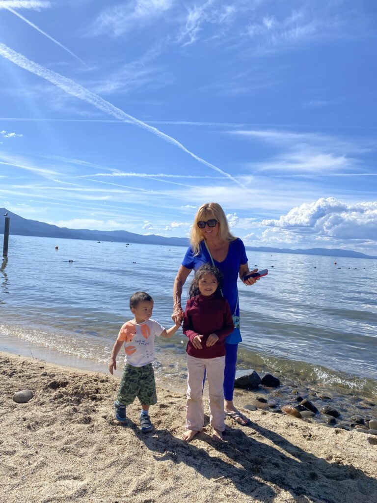 A family standing at the edge of Lake Tahoe with clear water and mountains