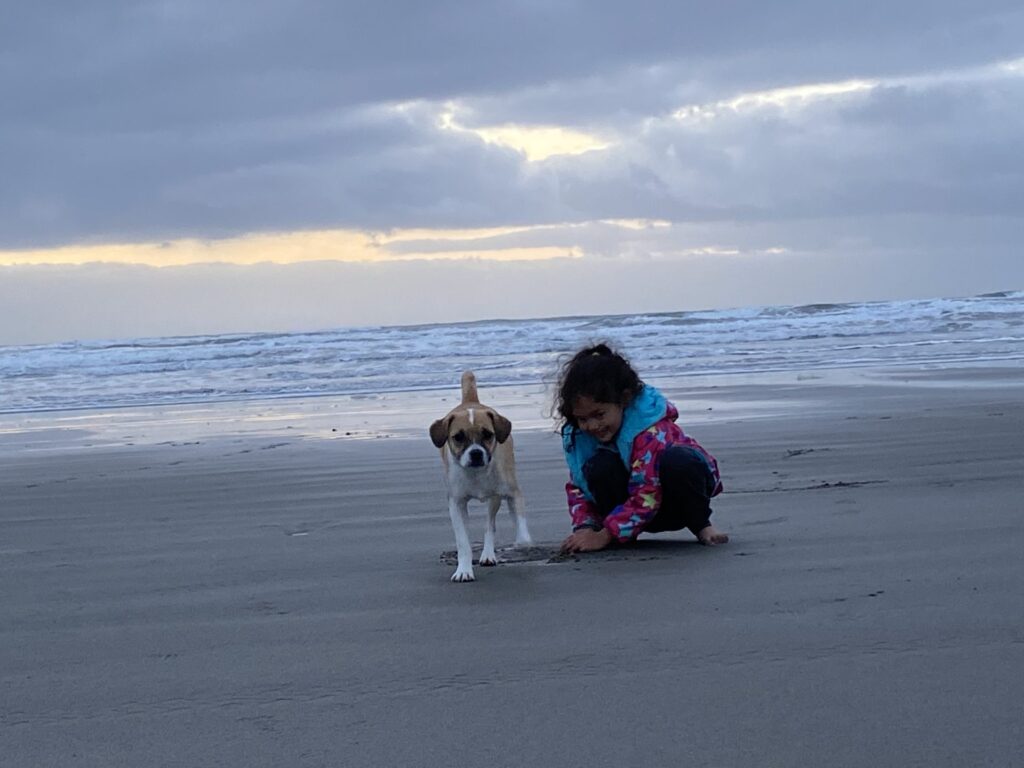 Child and dog on a wide grey beach near Warrenton, Oregon