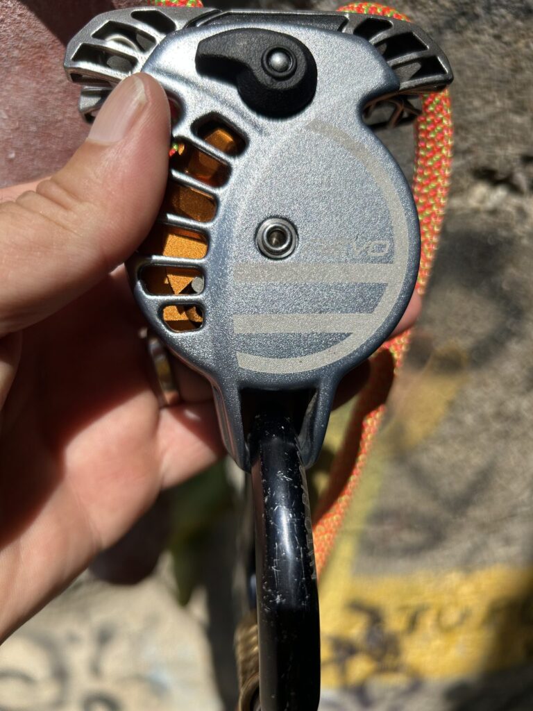 Close-up of a belay device held in a hand at the crag