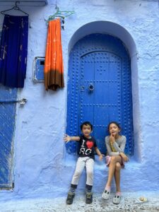 Two children sitting by a blue door in the old town of Chefchaouen, Morocco