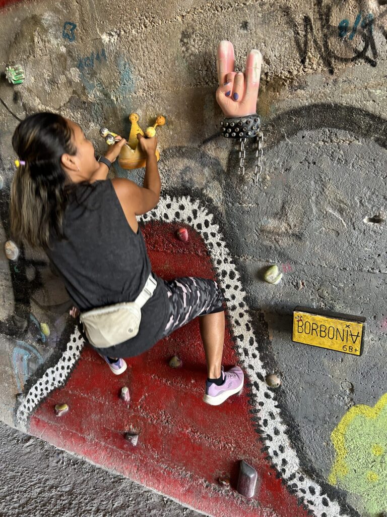 Child climbing a low wall with colorful holds in the Foixarda tunnel in Barcelona