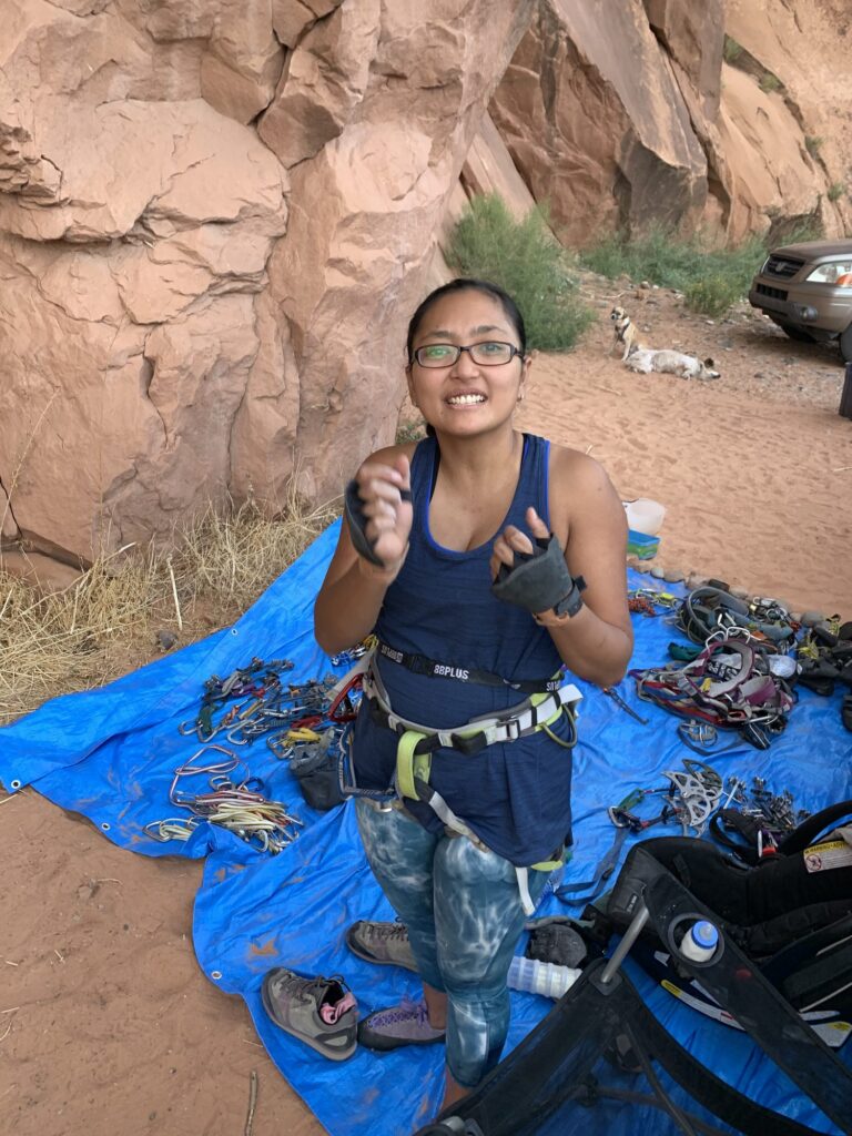 Climber in a harness sitting on a blue tarp with climbing gear at Wall Street, Moab