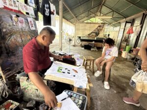 Artist painting a t-shirt for a child, Chiang Mai, Thailand