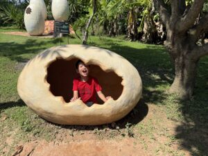 Child in a giant cracked egg sculpture, Chiang Mai, Thailand