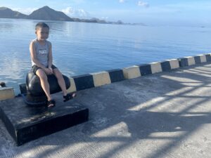 Child sitting on a pier bollard, Komodo Island, Indonesia