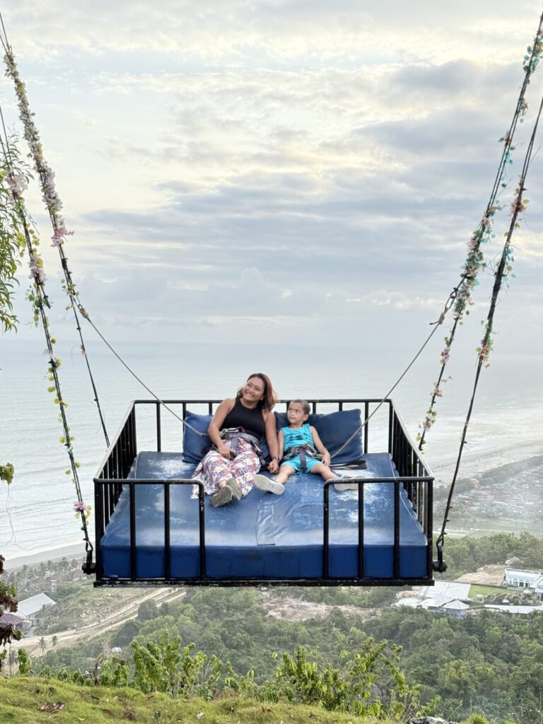 Family in a sky swing above the coast, Yogyakarta, Indonesia