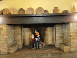 Kids standing by a big stone fireplace in a lodge in Yosemite