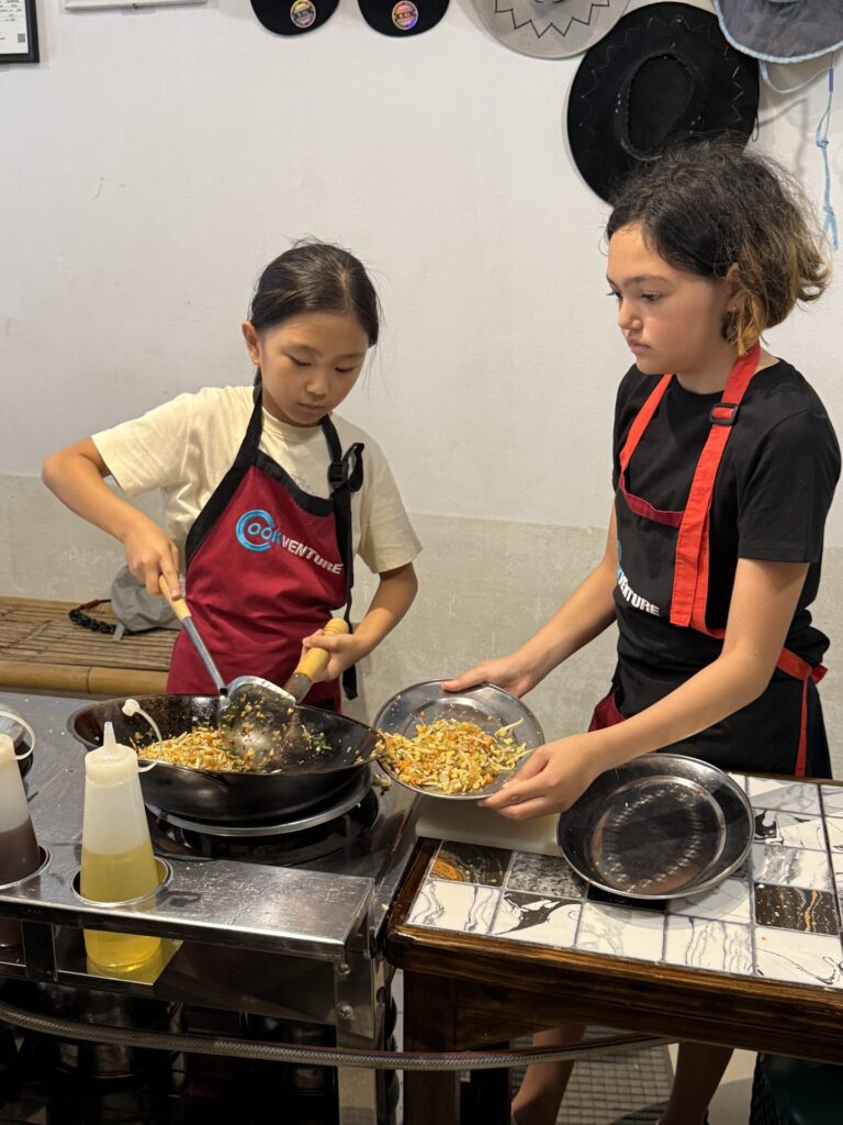 Kids cooking at woks in a Thai cooking class, Chiang Mai, Thailand