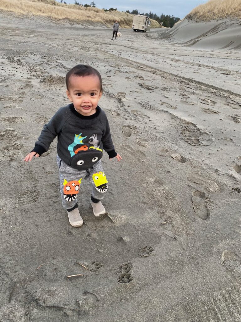 Toddler walking across grey sand dunes near Warrenton, Oregon