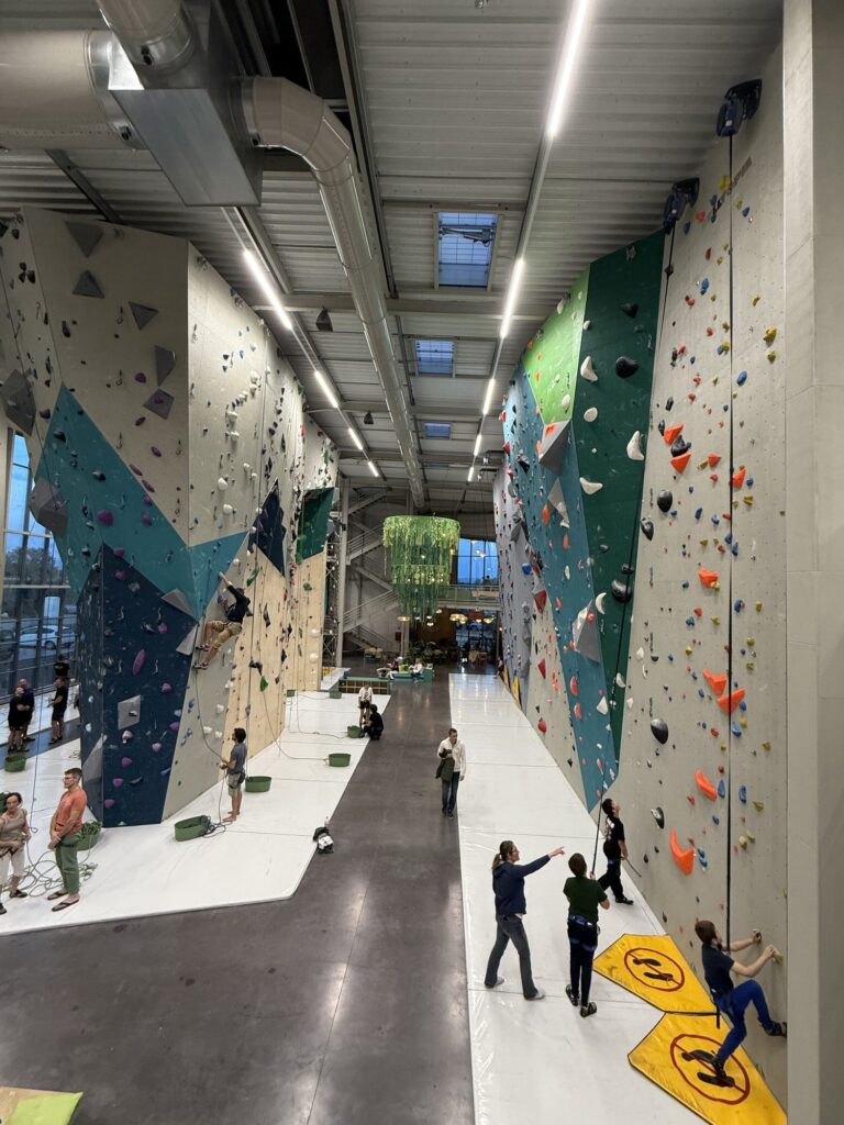 Children climbing and waiting their turn in a large indoor climbing gym