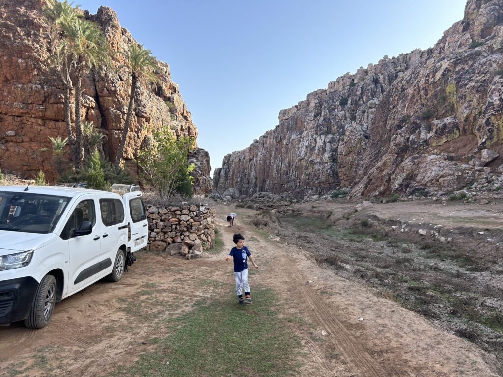 Child walking from the parked car toward a crag in a rocky Moroccan valley
