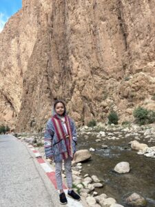Child standing by the river under the tall walls of Todra Gorge, Morocco